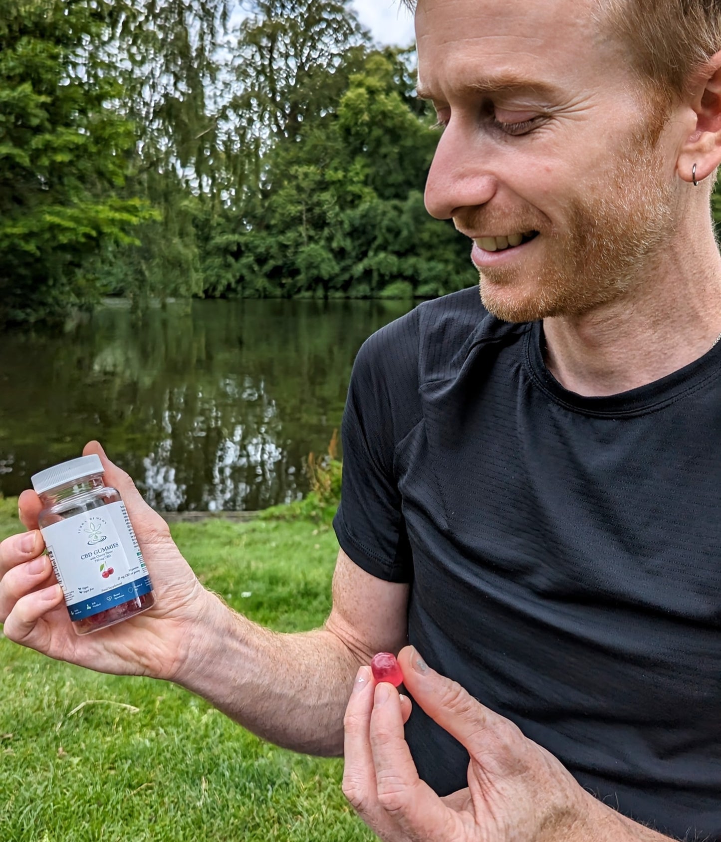 A person holding a bottle of Terra Remedy cherry-flavored CBD gummies in one hand and a single gummy in the other. The gummies are vegan, sugar-free, and contain broad-spectrum CBD for a tasty and convenient wellness option.